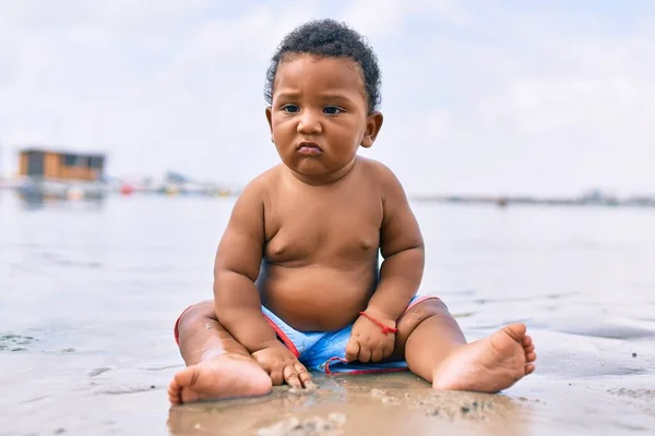 愛らしいアフリカ系アメリカ人の幼児がビーチに座っています — ストック写真