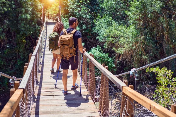 美丽的一对徒步旅行者穿着探险家的衣服和背包 在森林景观背景的跑道上走在后视镜上 — 图库照片