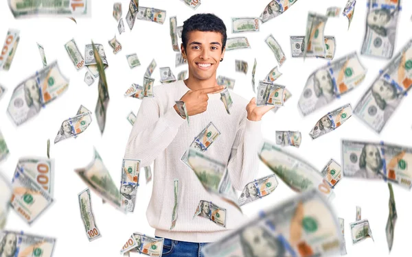 Genç Afrikalı Amerikalı sıradan kıyafetler giyen adam kameraya hayret ediyor ve gülümsüyor..