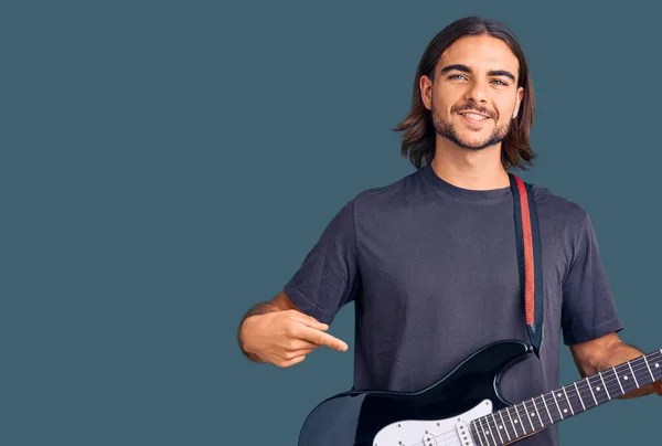 Jovem Homem Bonito Tocando Guitarra Elétrica Sorrindo Feliz Apontando Com — Fotografia de Stock