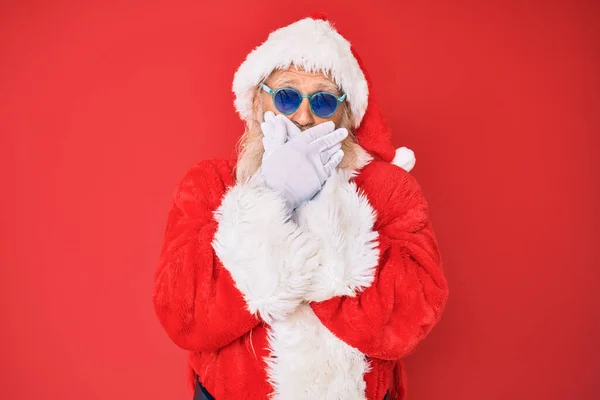 Staruszek Kostiumie Mikołaja Okularach Przeciwsłonecznych Zaszokowany Zakrywaniem Ust Rękami Przez — Zdjęcie stockowe