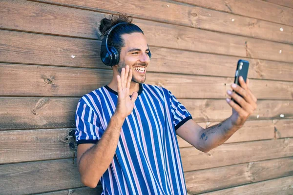 Молодой Латиноамериканец Улыбается Счастливо Используя Смартфон Видеозвонка Опираясь Стену — стоковое фото