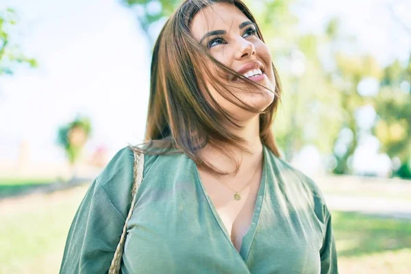 Genç İspanyol kadın gülümseyerek parkta mutlu bir şekilde yürüyor.