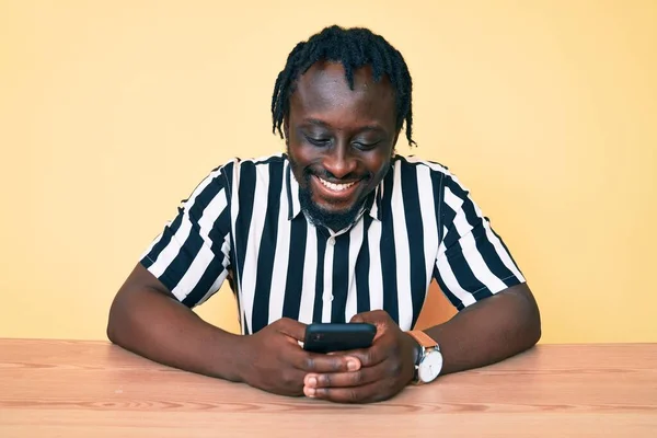 Ung Afrikansk Amerikansk Man Med Flätor Med Smartphone Sitter Bordet — Stockfoto
