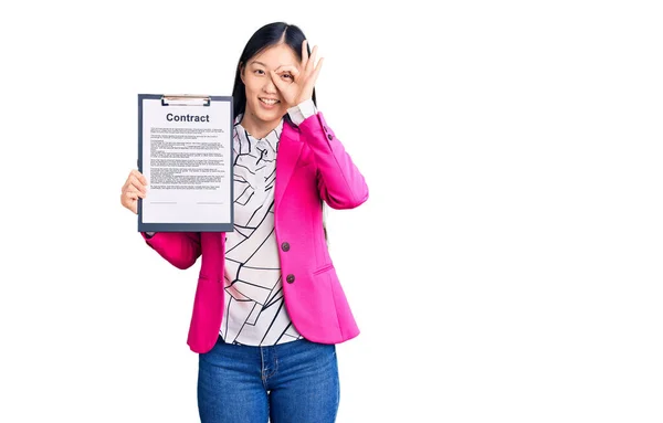 年轻美丽的中国女人拿着写字板 带着合同文件笑着快乐地做着 手拿着手签 用手指看 — 图库照片