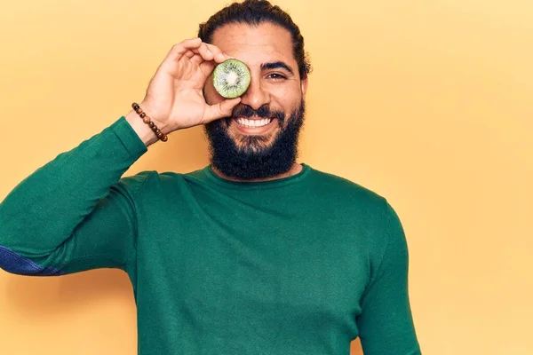 Ung Arabisk Man Håller Kiwi Ser Positiv Och Glad Stående — Stockfoto