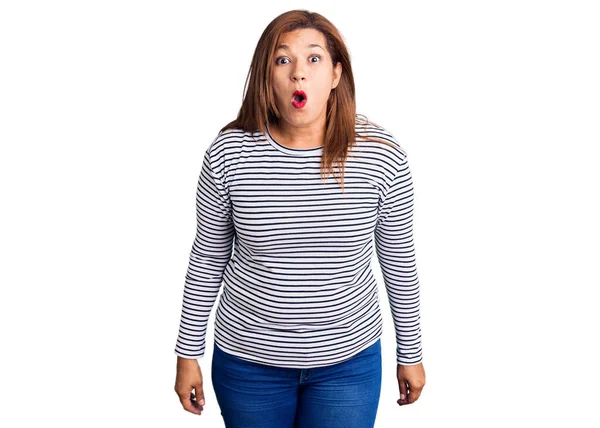 Orta yaşlı, sıradan kıyafetler giyen, ağzı açık, korkmuş, şaşırmış bir Latin kadın. 