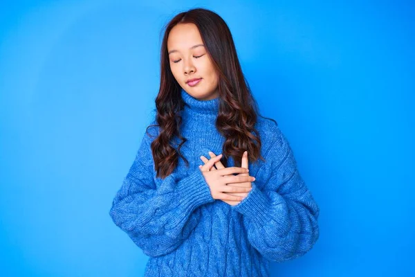 若い美しい中国の女の子は 目を閉じて胸に手で笑みを浮かべてカジュアルな冬のセーターを着て顔に感謝のジェスチャー 健康の概念 — ストック写真