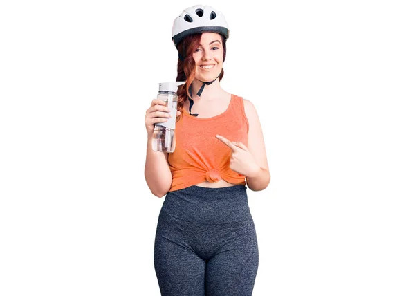 若いです美しいです女性身に着けています自転車ヘルメットと保持水ボトル笑顔幸せなポインティングとともに手と指 — ストック写真