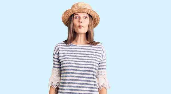 狂気とコミカルなジェスチャーで魚の顔を作る夏の帽子をかぶって美しい白人女性 面白い表現 — ストック写真