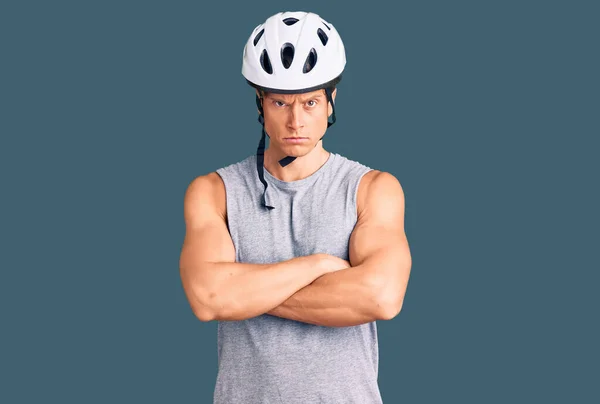 Young handsome man wearing bike helmet skeptic and nervous, disapproving expression on face with crossed arms. negative person.