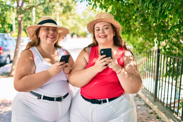 2プラスサイズ太りすぎ姉妹双子女性とともにスマートフォン屋外で晴れた日に — ストック写真