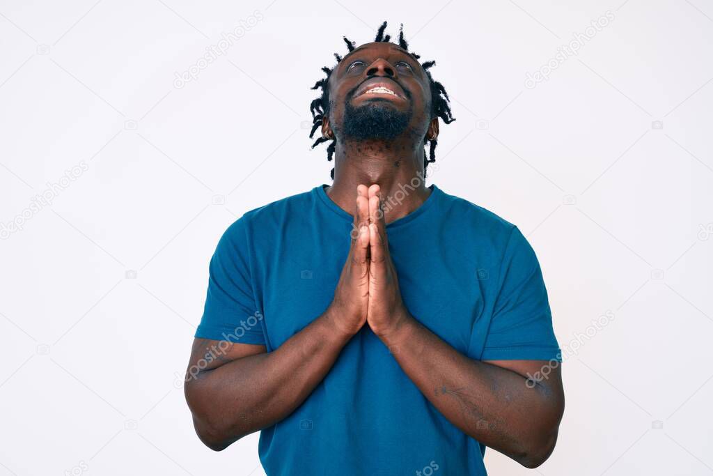 Young african american man with braids wearing casual clothes begging and praying with hands together with hope expression on face very emotional and worried. begging. 