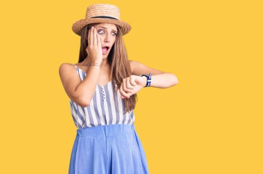 Yaz şapkası takan genç, güzel sarışın kadın saate bakıyor. Endişeli, geç kalmaktan korkuyor. 