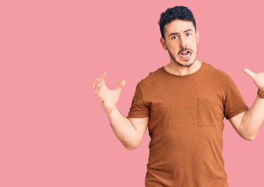 Gündelik kıyafetler giyen genç İspanyol adam deli gibi bağırıyor ve agresif bir ifade ve kollarla bağırıyor. hüsran kavramı. 