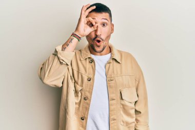 Dövmeleri olan, sıradan kahverengi kot ceket giyen, şaşırmış yüzüyle şaşırmış, parmaklarından bakan yakışıklı bir adam. İnançsız ifade. 