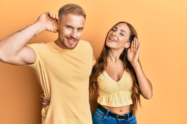 Genç bir çift kız arkadaş ve erkek arkadaş kucaklaşıp yan yana sırıtarak dedikodu ve dedikoduları dinliyorlar. Sağırlık kavramı. 