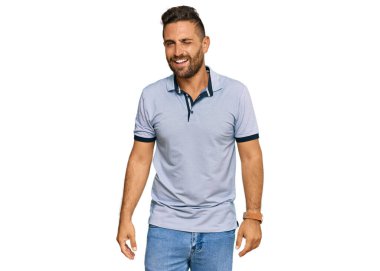 Sakallı, sıradan kıyafetler giyen, kameraya seksi bir ifadeyle bakan, neşeli ve mutlu yüzlü yakışıklı bir adam.. 