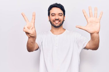 Gündelik kıyafetler giyen genç İspanyol adam yedi numarayı gösterip işaret ederken kendinden emin ve mutlu bir şekilde gülümsüyor.. 