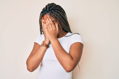 Saçları günlük beyaz tişörtlü, suratını ellerle kapatıp ağlayan Afro-Amerikalı genç bir kadın. depresyon kavramı. 