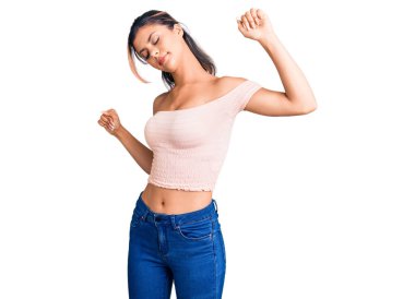 Genç, güzel bir kadın, günlük giysiler giyiyor, geriniyor, yorgun ve rahat, uykulu ve sabahın erken saatleri için esniyor. 