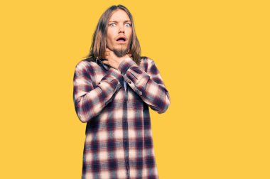 Uzun saçlı, hippi tişörtü giyen yakışıklı beyaz adam bağırıyor ve boğuluyor çünkü acı verici bir boğulma. Sağlık problemi. Boğulma ve intihar konsepti. 