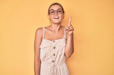 Yazlık elbise giyen güzel beyaz kadın bir numarayı gösterip işaret ederken kendine güvenen ve mutlu bir şekilde gülümsüyor.. 