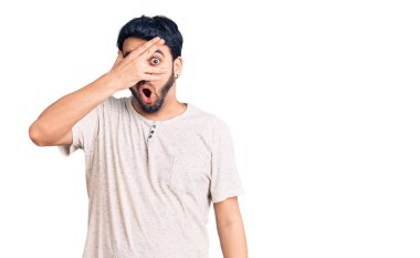 Gündelik kıyafetler giyen genç İspanyol adam şok içinde yüzünü ve gözlerini kapayarak utanmış ifadesiyle parmaklarından bakıyor.. 