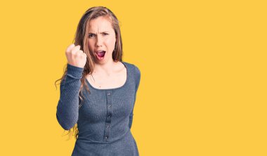 Genç, güzel, sarışın bir kadın. Kızgın ve kızgın. Öfkeyle bağırırken yumruğunu kaldırıyor. öfke ve agresif konsept. 