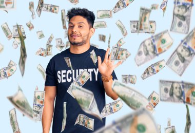 Yakışıklı, Latin Amerikalı, güvenlik tişörtü giyen, feragat eden mutlu, güler yüzlü, dost canlısı bir jest.