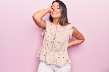 Genç, güzel, esmer, sıradan kıyafetler giyen mutlu ve kendinden emin bir kadın. İzole edilmiş pembe arka planda yüzünde bir gülümsemeyle duruyorum.