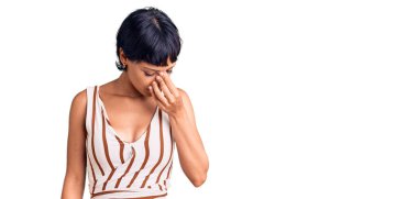 Kısa saçlı, yaz kıyafeti giyen, burnu ve gözleri ovuşturmaktan yorgun, yorgun ve başı ağrıyan esmer bir kadın. Stres ve hüsran kavramı. 