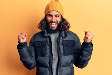 Gündelik kışlık kıyafetler giyen genç Arap adam gururla bağırıyor zaferi ve başarıyı kutluyor. Kollarını kaldırıp heyecanla bekliyor. 