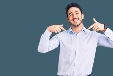 İş kıyafetleri giymiş genç İspanyol bir adam. Kendine güvenen, yüzünde gülümseme olan, kendini gururlu ve mutlu gösteren bir adam.. 