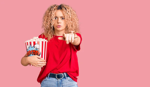 Young Blonde Woman Curly Hair Eating Popcorn Pointing Finger Camera — Stock Photo, Image