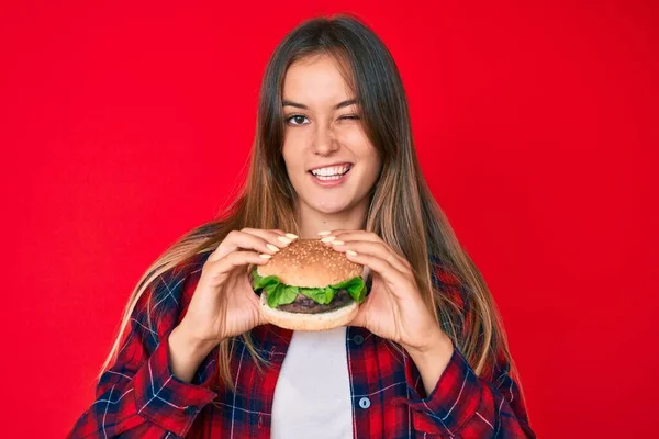 Beautiful Caucasian Woman Eating Tasty Classic Burger Winking Looking Camera — Stock Photo, Image