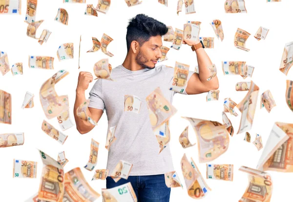 Yakışıklı, Latin Amerikalı, sıradan tişörtler giyen, gururla gülümseyen kol kaslarını gösteren genç adam. fitness konsepti.