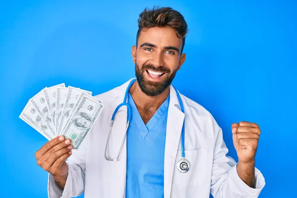 Joven Hispano Vistiendo Uniforme Médico Sosteniendo Dólares Gritando Orgulloso Celebrando — Foto de Stock