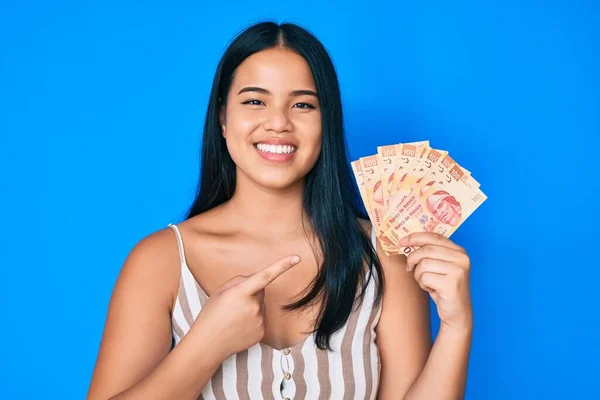 Young Beautiful Asian Girl Holding Mexican Pesos Smiling Happy Pointing — Stock Photo, Image