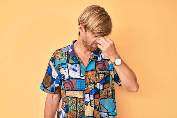 Yazlık gömlek giyen genç sarışın adam yorgun burnu ve gözleri ovuşturup yorgun ve baş ağrısı çekiyor. Stres ve hüsran kavramı. 