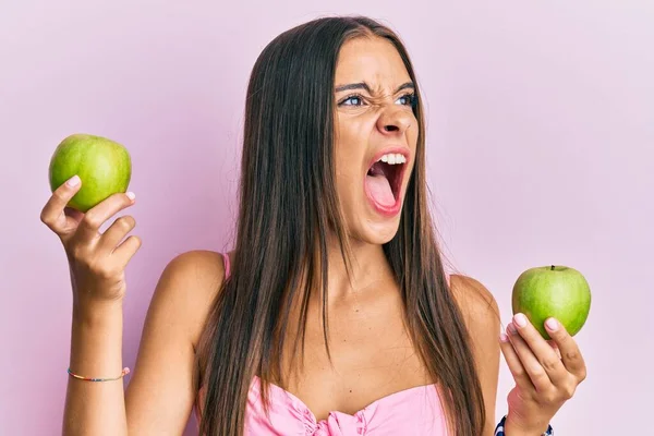 Mujer Hispana Joven Sosteniendo Manzanas Verdes Enojada Loca Gritando Frustrada —  Fotos de Stock