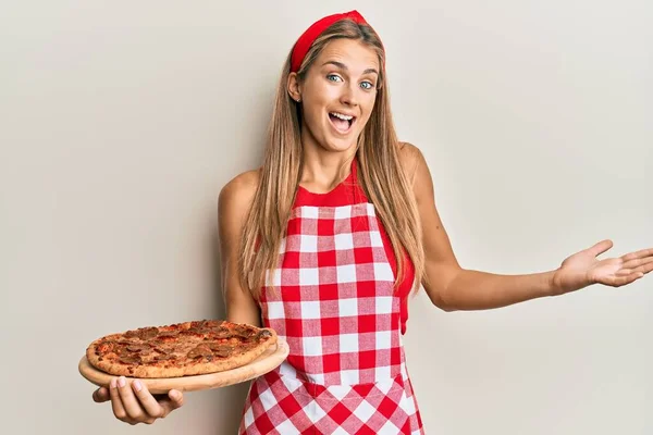 Jovem Loira Vestindo Avental Profissional Padeiro Segurando Pizza Italiana Celebrando — Fotografia de Stock