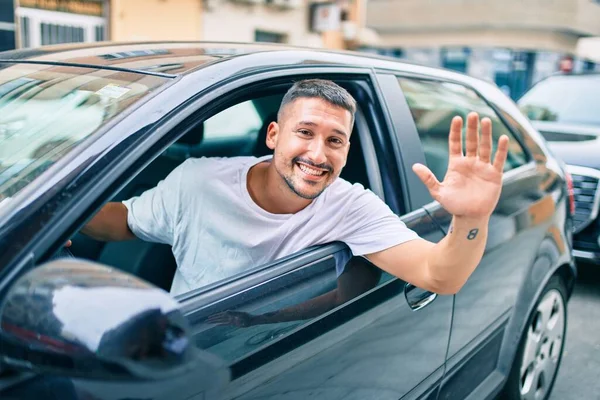 Genç İspanyol adam gülümsüyor, mutlu bir şekilde arabada oturuyor..