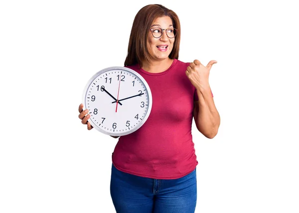 Mujer Latina Mediana Edad Sosteniendo Gran Reloj Apuntando Con Pulgar —  Fotos de Stock