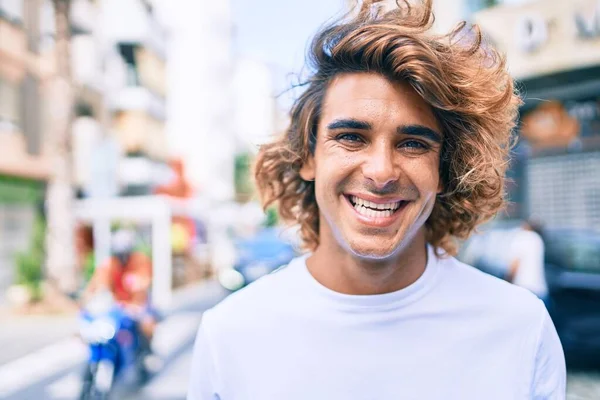 Genç, yakışıklı, gülümseyen bir İspanyol. Şehrin caddesinde mutlu bir şekilde yürüyor.