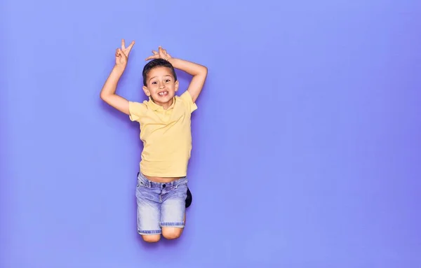 Adorable Niño Con Ropa Casual Saltando Sobre Fondo Púrpura Aislado —  Fotos de Stock