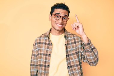 Gündelik kıyafetler giyen ve gözlüklü genç, yakışıklı İspanyol adam başarılı bir fikri işaret ediyor. Heyecanlı ve mutlu. Bir numara.. 