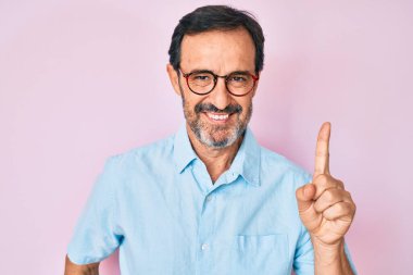 Orta yaşlı İspanyol bir adam gündelik kıyafetler ve gözlük takıyor. Bir fikir veya soruyla gülümsüyor. Mutlu bir yüzle işaret ediyor. 