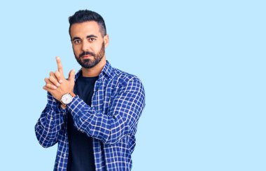 Latin asıllı genç adam gündelik giysiler giyiyor. Elinde sembolik bir silah var. El hareketleriyle cinayet silahlarıyla oynuyor. 