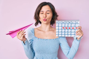 Genç ve güzel bir kadın kalp takvimi tutuyor ve kameraya bakıyor. Öpüşme sahnesi çekiliyor ve çok seksi. aşk ifadesi. 